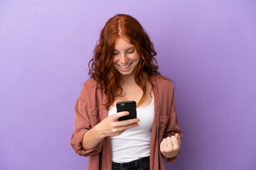 Teenager redhead girl over isolated purple background surprised and sending a message