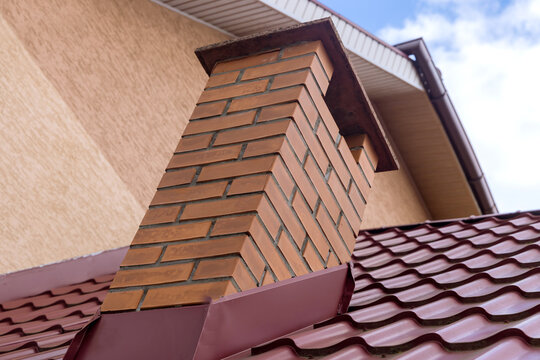 Chimney on the red metal roof tiles shingles with roofing construction
