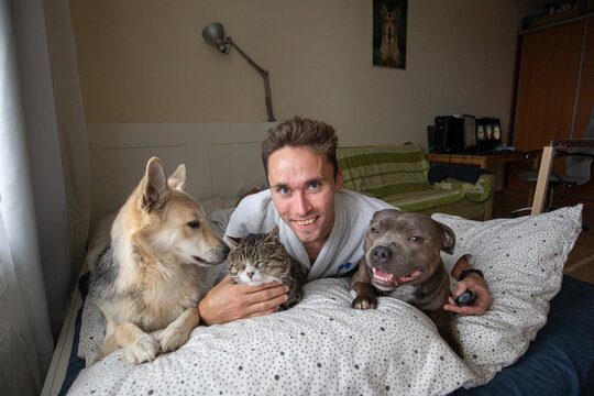 Pleased young man looking at camera and taking selfie with pets