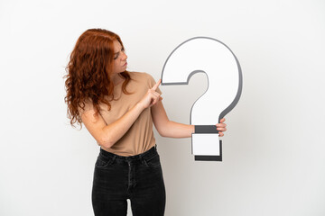 Teenager redhead girl isolated on white background holding a question mark icon