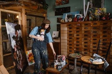 Young woman artist creating painting while working in her studio