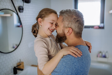 Father kissing his little daughter in bathroom.