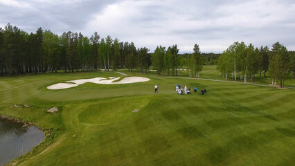 Obraz premium Golfers hitting golf shot with club on course while on summer vacation, aerial