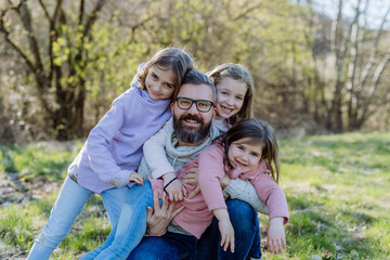 Fototapeta na wymiar Father with his three little daughters looking at camera in spring nature together.