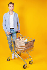 A young male and shopping cart full with groceries