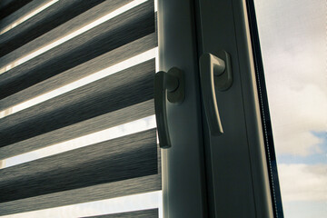 a plastic window with a roller blind and a mosquito net against a blue sky