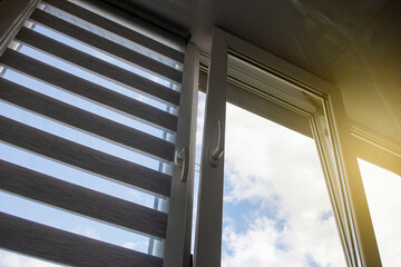 a plastic window with a roller blind and a mosquito net against a blue sky