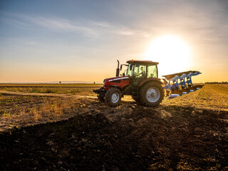 Farmer in tractor plowing preparing stubble field cultivating for seeding crops.