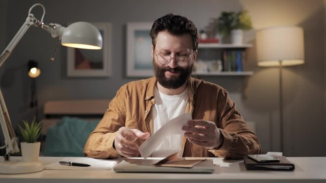 Man opens letter negative emotions. Upset remote worker receives tax receipt. Freelancer at home office at night upset about received document
