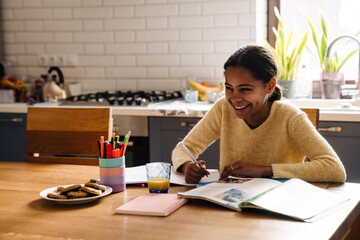 Black happy girl laughing while doing homework at home