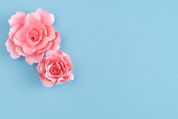 Paper roses on blue background. Copy space. Greeting card.