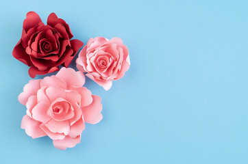 Paper roses on blue background. Copy space.