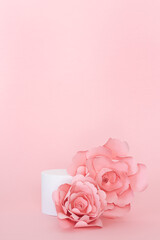 Blank circular platform for product presentation with paper roses on pink background. Copy space. Vertical photo.