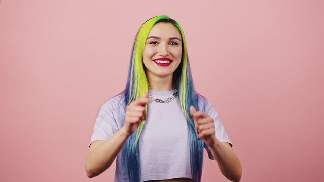 Gotcha. Young happy playful woman with rainbow colored hair pointing fingers to camera and smiling