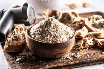 A wooden bowl full of breadcrumbs and old dry bread around