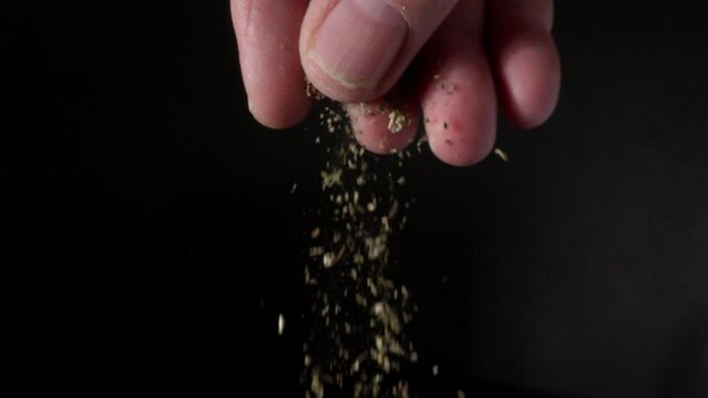 A chef sprinkling dried herbs, rough plaster background. 20x slow motion
