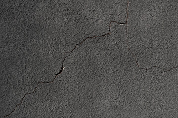 Gray wall with a crack. Texture of rough plaster with uneven granular coating