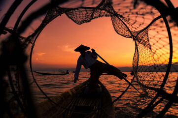 Front view of silhouette of a traditional Burmese fisherman on Inle Lake at sunset in Myanmar