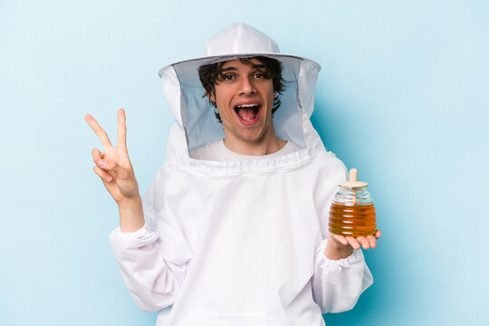 Young caucasian beekeeper man isolated on blue background showing number two with fingers.
