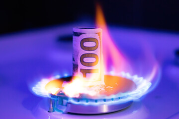 A bill is burning on a gas fire, close-up. Dollar deficit
