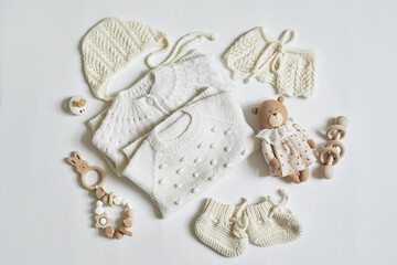 Children's knitwear. Jumper, hat, booties, socks. Wooden teether, nipple. Baby shower party. Preparing for childbirth. Flat lay.