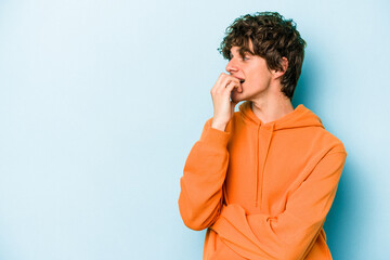 Young caucasian man isolated on blue background relaxed thinking about something looking at a copy space.