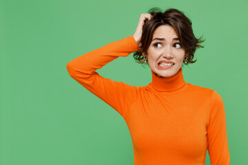 Young puzzled mistaken pensive sad woman 20s wear casual orange turtleneck look aside scratch hold...