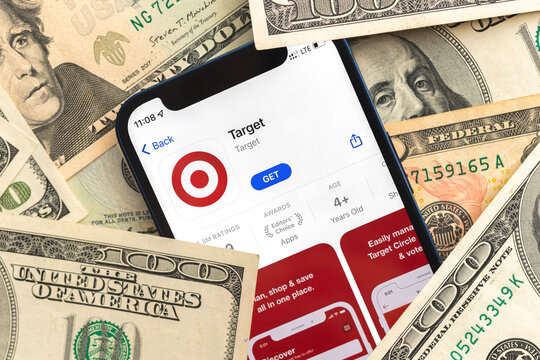 Target shopping app logo on mobile phone screen. Business background with dollar money banknotes photo