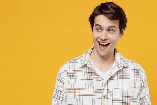Young smiling surprised happy caucasian man 20s wearing white casual shirt look aside on workspace area mock up isolated on plain yellow background studio portrait. People lifestyle emotions concept.