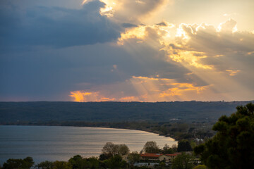 Mystical dramatic cloudy sky with the sun behind the clouds and rays of light on the lake. Photo in artistic style