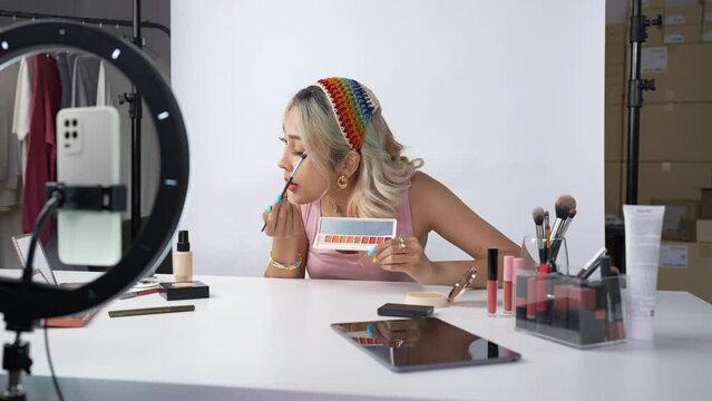 Young beautiful Asian woman and professional beauty make up artist vlogger or blogger recording makeup tutorial to share on website or social media. Business online influencer on social media concept.