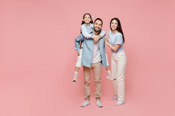 Full body young parents mom dad with child kid daughter teen girl in blue clothes giving piggyback...