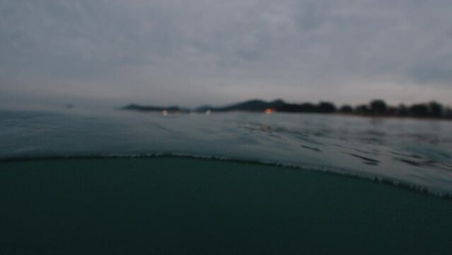 Ocean at night. Splitted view of the murky water and lights on the coast