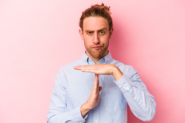 Young caucasian man isolated on pink background showing a timeout gesture.