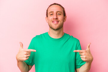 Fototapeta premium Young caucasian man isolated on pink background points down with fingers, positive feeling.