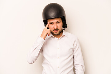 Hispanic business man going to work with motorcycle isolated on white background pointing temple with finger, thinking, focused on a task.