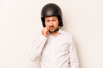 Hispanic business man going to work with motorcycle isolated on white background with fingers on lips keeping a secret.