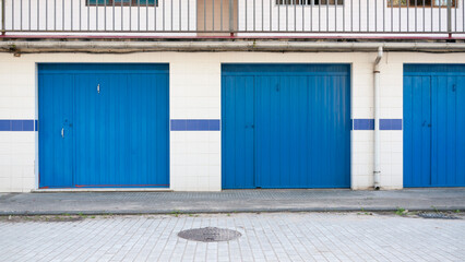 Obraz na płótnie Canvas Puertas de garage en diferentes tono de azul en calle