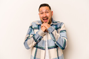Young hispanic man isolated on white background praying for luck, amazed and opening mouth looking to front.