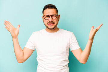 Naklejka premium Young hispanic man isolated on blue background screaming to the sky, looking up, frustrated.