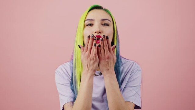 Love concept. Close up portrait of young peaceful happy woman with bright multicolored hair sending blow kiss to camera