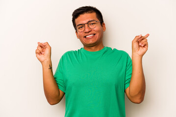 Fototapeta premium Young hispanic man isolated on white background pointing to different copy spaces, choosing one of them, showing with finger.