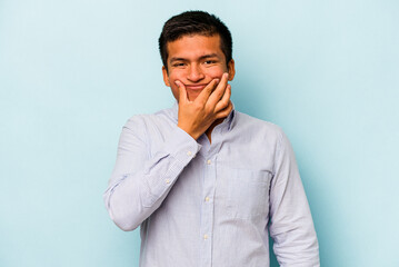 Young hispanic man isolated on blue background doubting between two options.
