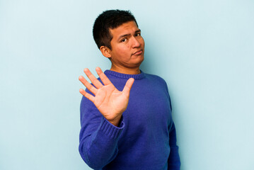 Young hispanic man isolated on blue background rejecting someone showing a gesture of disgust.