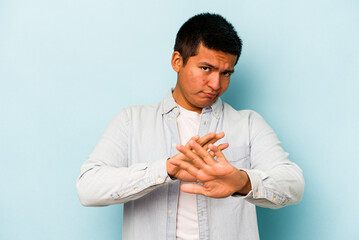 Young hispanic man isolated on blue background doing a denial gesture