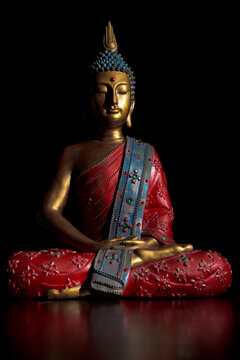 Sitting buddha statue in lotus position. The statue is in bright colors and inlaid with colored crystals.
