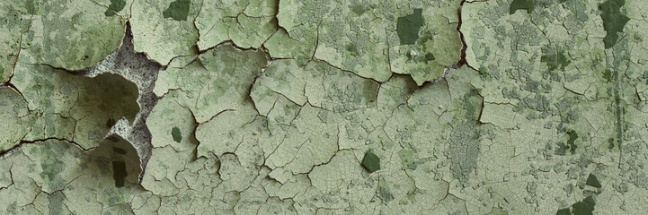 Peeling paint on the wall. Panorama of a concrete wall with old cracked flaking paint. Weathered rough painted surface with patterns of cracks and peeling. Wide panoramic grungy texture for background