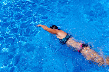Fototapeta na wymiar Real swimmer woman in a pool in summer going hard into the water.