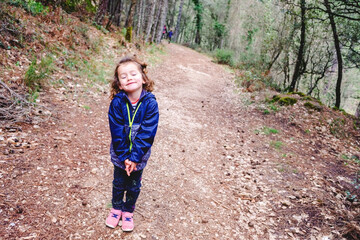 Funny little girl walks through a forest taking a family walk in autumn.