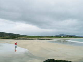 BOY WALKING ALONG THE DESERTED BEACH ON A RAINY DAY © Beatriz